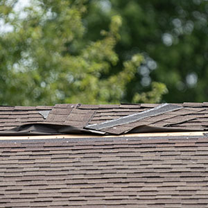 Close-up of a roof that has some shingles torn off due to storm damage